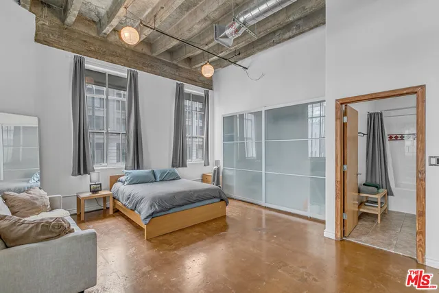 a spacious bedroom with a bed and glass walk in closet