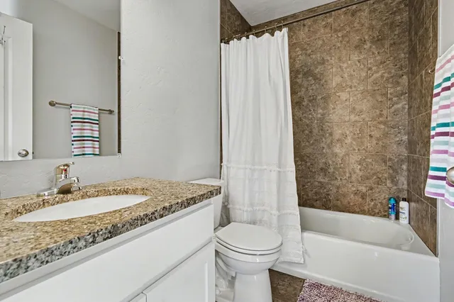 a bathroom with a granite countertop sink toilet and shower