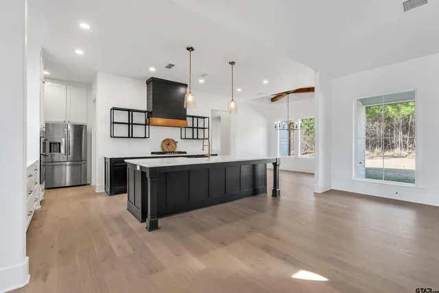 a large kitchen with stainless steel appliances kitchen island a large counter top and a wooden floors