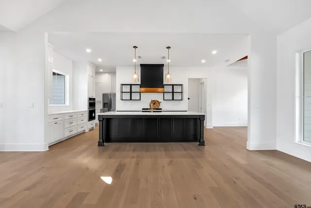 a large kitchen with stainless steel appliances a large counter top a stove a sink and a refrigerator