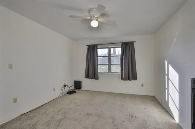 an empty room with windows and ceiling fan