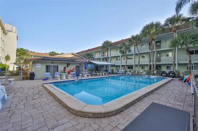 a view of a white house with a swimming pool and sitting area