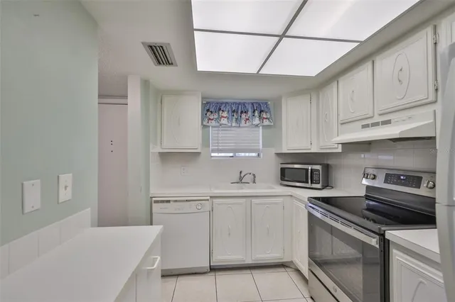 a kitchen with white cabinets and appliances