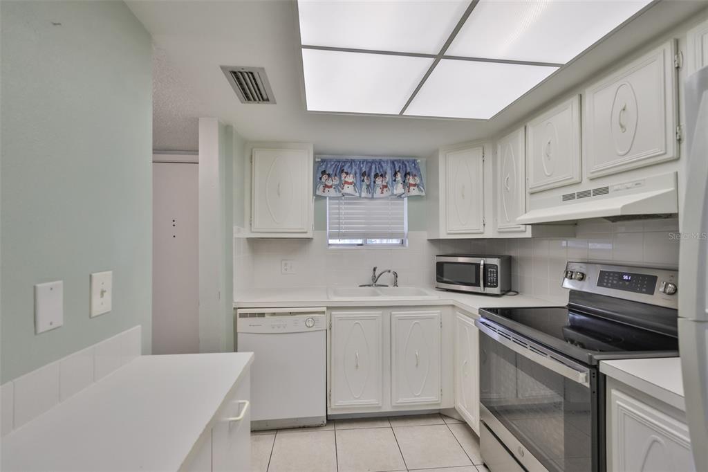 801 83rd Avenue North, Unit 118 St. Petersburg, FL 33702 - Photo 10 of 37 a kitchen with white cabinets and appliances