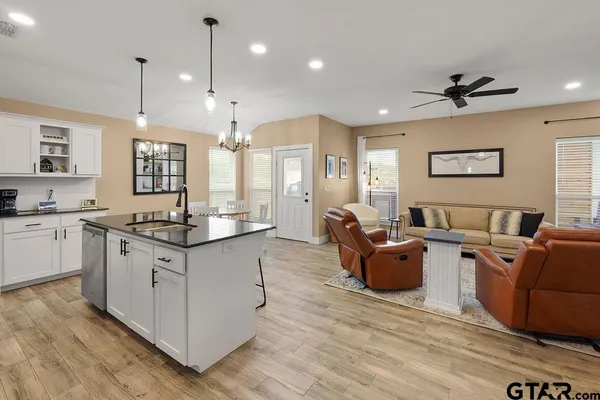a large living room with stainless steel appliances kitchen island granite countertop wooden floor a large window and a sink