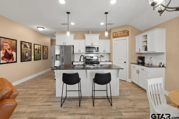 a kitchen with stainless steel appliances kitchen island granite countertop a stove a sink and a refrigerator