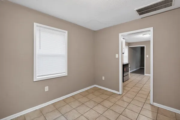 a view of an empty room with window and chandelier fan