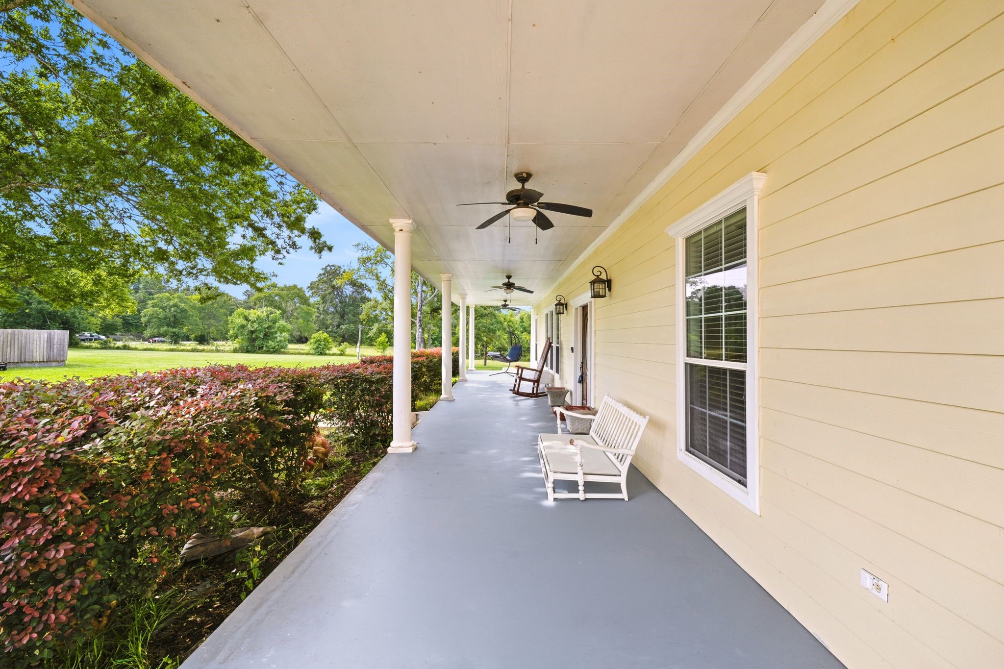 144 Wood Farm Road Huntsville, TX 77320 - Photo 5 of 50 Stretch out and unwind on the expansive covered front porch, designed for year-round enjoyment. Complete with multiple ceiling fans and plenty of room for rocking chairs or outdoor seating, this inviting space is the perfect place to enjoy your morning coffee, relax in the evening, and take in the peaceful views of the surrounding property.