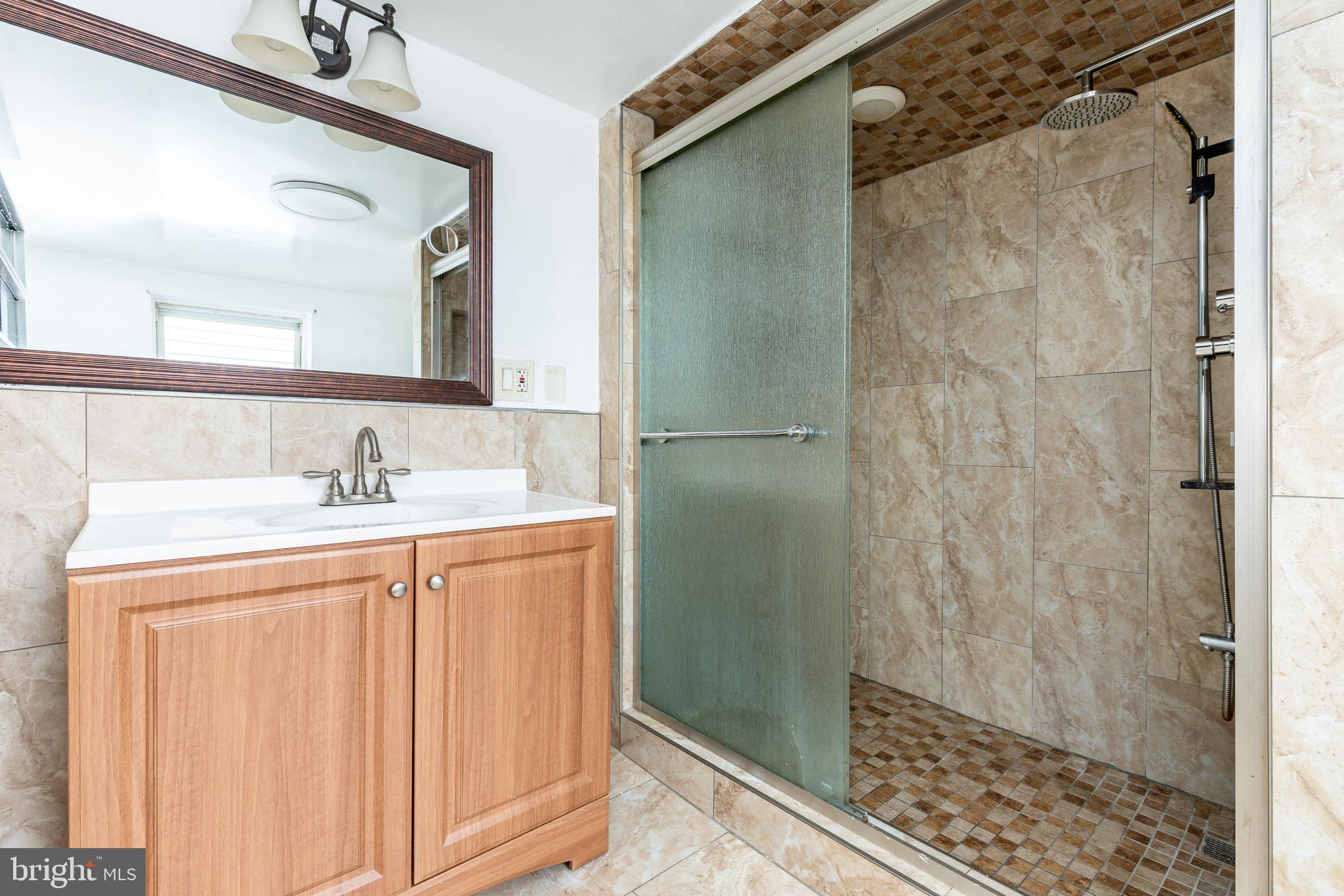 2726 Edgemont Street Philadelphia, PA 19134 - Photo 18 of 32 a bathroom with a granite countertop shower sink and mirror