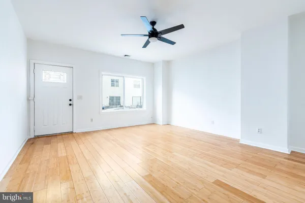 a view of empty room with wooden floor and fan