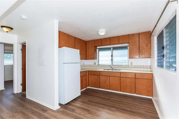 a kitchen with stainless steel appliances granite countertop a refrigerator a sink dishwasher a stove and white countertops with wooden floor