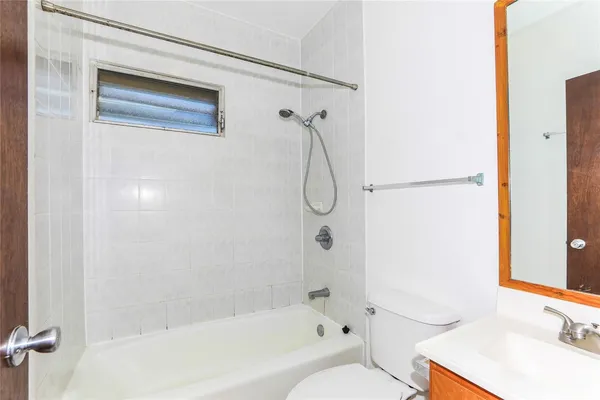 a bathroom with a granite countertop bathtub shower sink vanity and a toilet