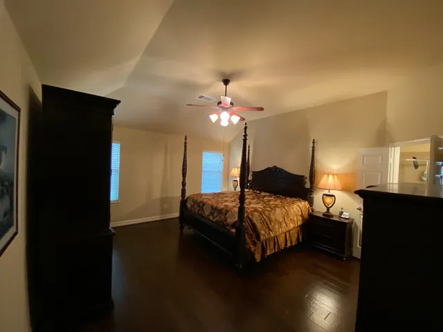 a spacious bedroom with a bed and wooden floor