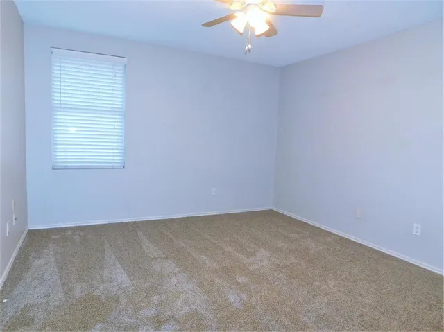 an empty room with a chandelier fan and window
