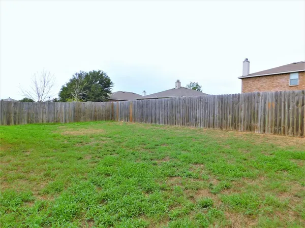 a view of a backyard with grass and wooden fence