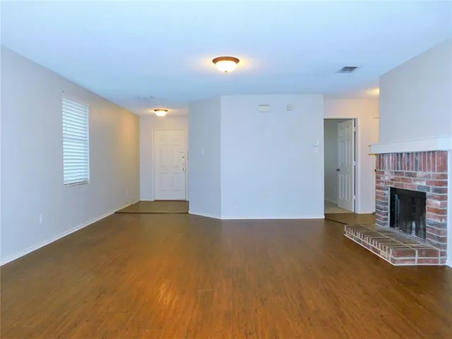 a view of empty room with fireplace and wooden floor