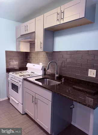 a kitchen with sink a stove and cabinets