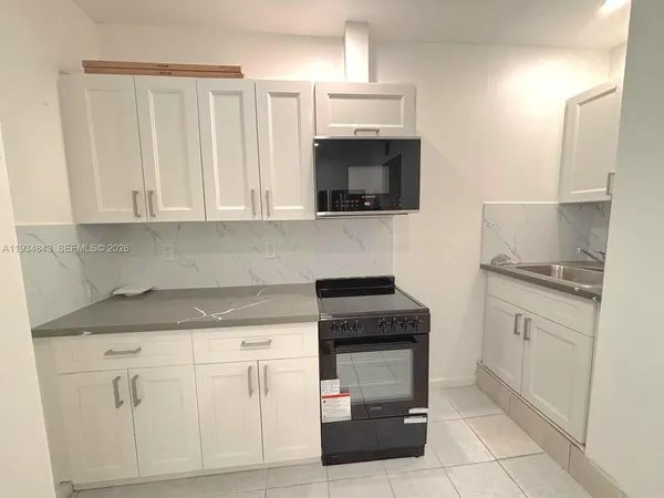 a kitchen with white cabinets and appliances