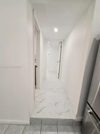 a view of a refrigerator in kitchen and an empty room
