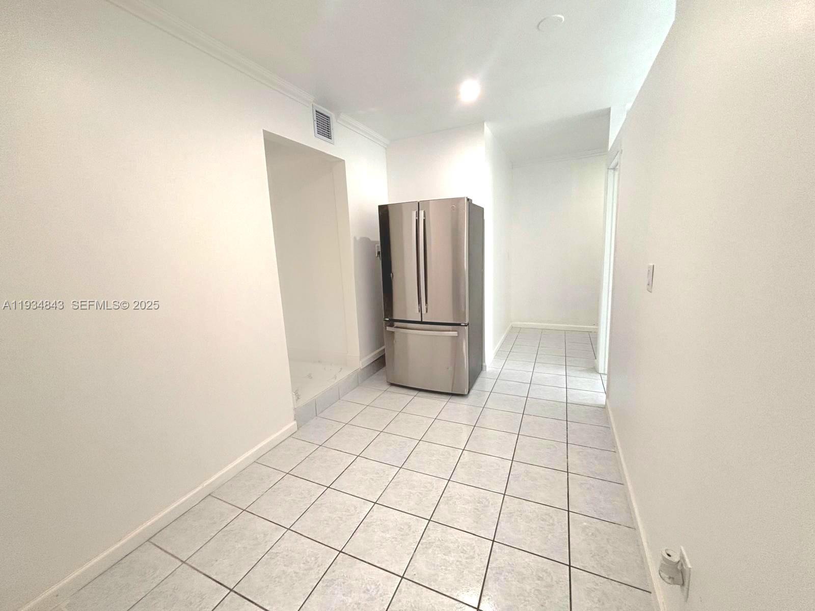 14402 Southwest 111th Street, Unit 14402 Miami, FL 33186 - Photo 10 of 21 a view of a refrigerator in kitchen and an empty room