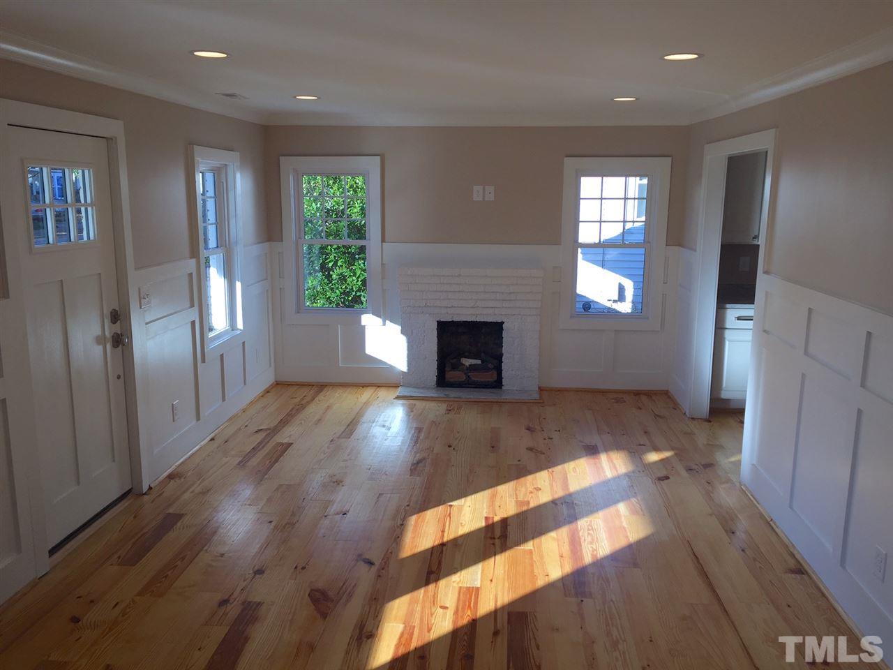 3132 Stanhope Avenue Raleigh, NC 27607 - Photo 2 of 11 an empty room with windows a fireplace and wooden floor