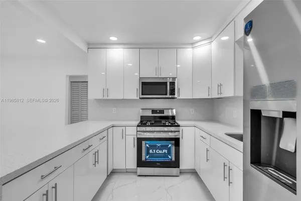 a kitchen with white cabinets and appliances