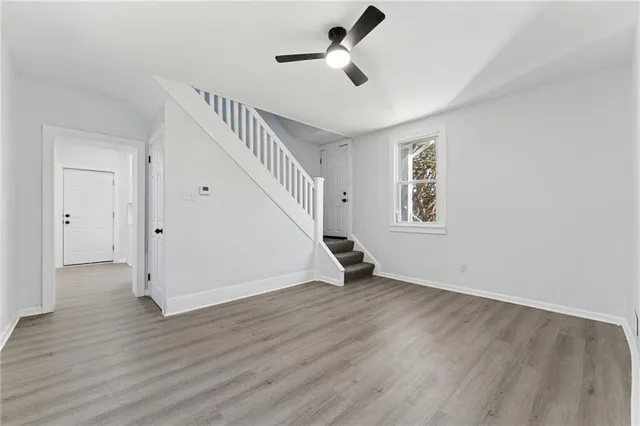 a view of an empty room with wooden floor and a ceiling fan