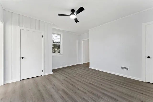 an empty room with wooden floor ceiling fan and windows