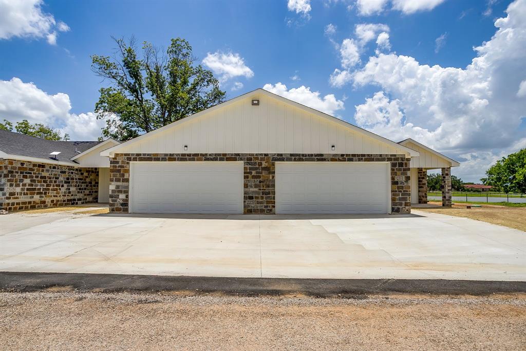 133 Winners Circle, Unit 202 Weatherford, TX 76087 - Photo 2 of 20 View of front of property with stone siding, a garage, and concrete driveway