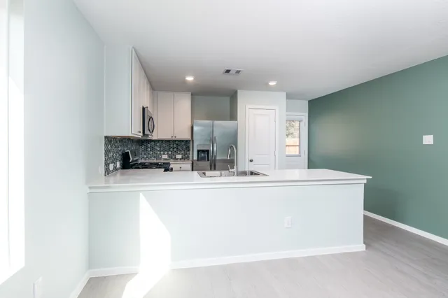 a view of kitchen with stainless steel appliances granite countertop refrigerator sink and cabinets