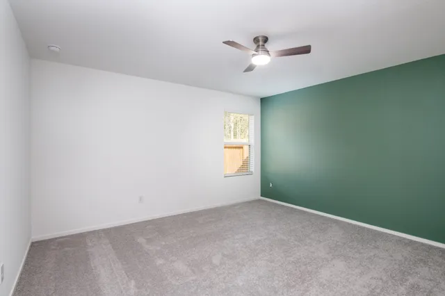 an empty room with a window and a fan