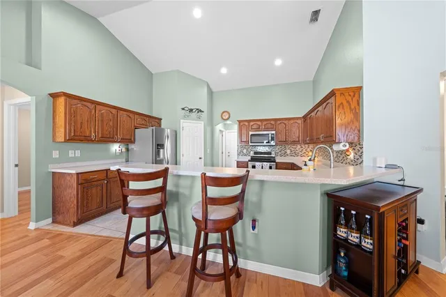 a kitchen with stainless steel appliances granite countertop a table chairs sink and cabinets