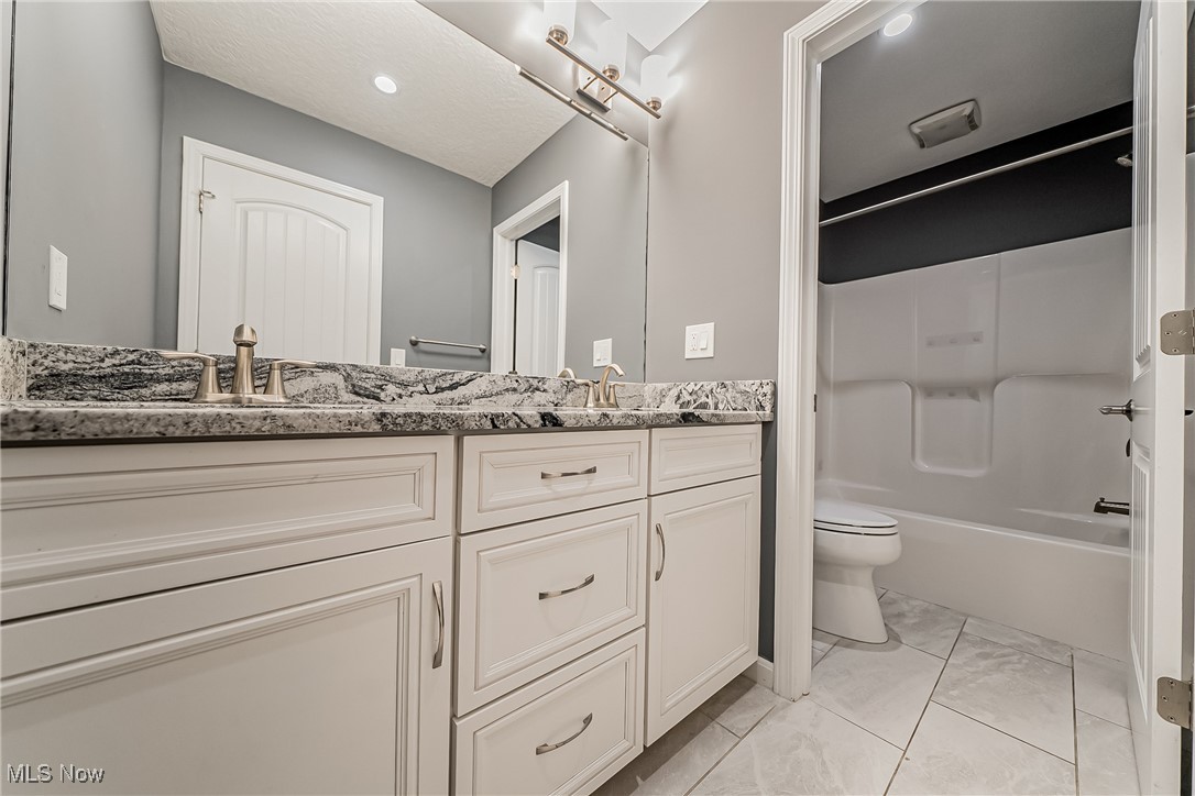 5270 Brainard Road Solon, OH 44139 - Photo 16 of 45 Hall Bathroom with double vanity, and separate shower / washtub combination, and toilet with light tile patterned flooring