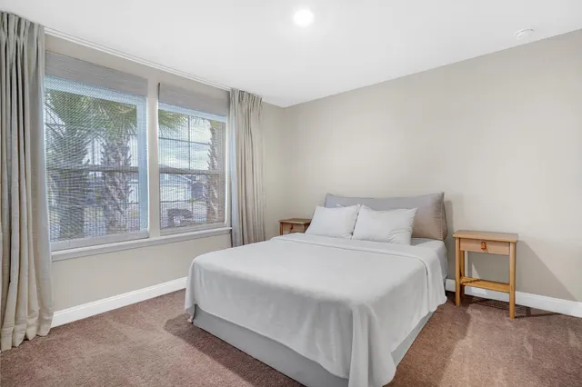 a bedroom with a bed lamp and a large window