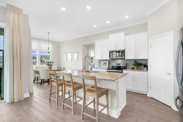 a kitchen with stainless steel appliances white cabinets and wooden floor