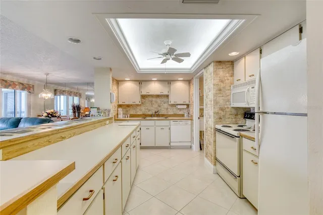 a kitchen with stainless steel appliances granite countertop a refrigerator a sink dishwasher a stove and white cabinets with wooden floor