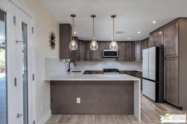 a kitchen with stainless steel appliances granite countertop a sink a stove a refrigerator a center island and cabinets