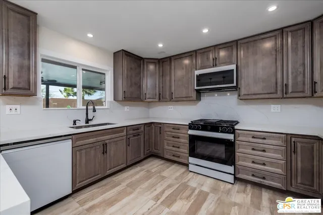 a kitchen with stainless steel appliances granite countertop wooden cabinets a stove a sink and a microwave