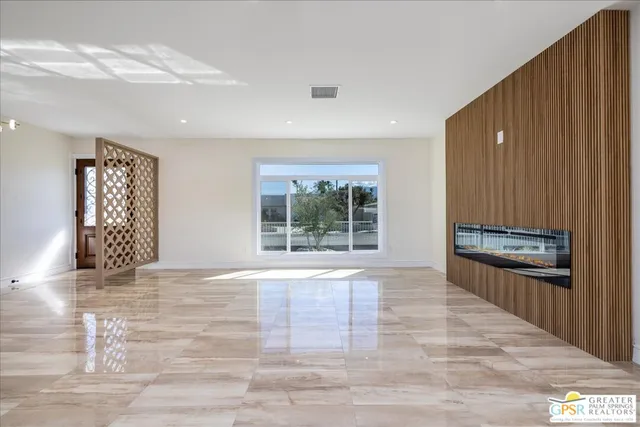 a view of an empty room with a window and a kitchen