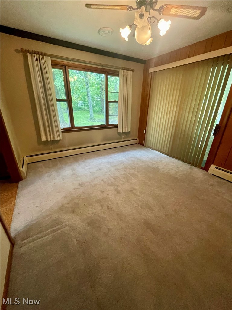 7815 Cemetery Road Vermilion, OH 44089 - Photo 18 of 43 Spare room featuring ornamental molding, ceiling fan, carpet, and baseboard heating