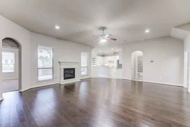 a view of an empty room with a fireplace and wooden floor
