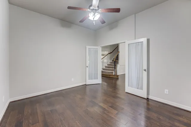 a view of an empty room with wooden floor ceiling fan