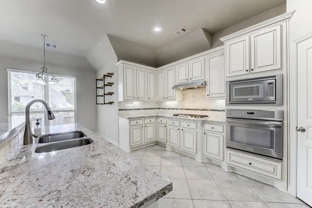 a kitchen with kitchen island granite countertop a stove a sink and a microwave