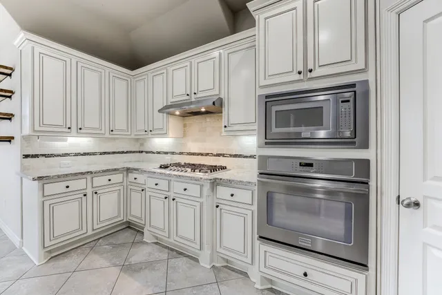 a kitchen with granite countertop white cabinets stainless steel appliances