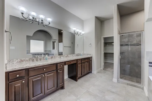 a spacious bathroom with a granite countertop sink a large mirror and a shower