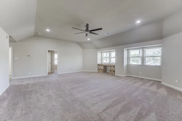 an empty room with windows and ceiling fan