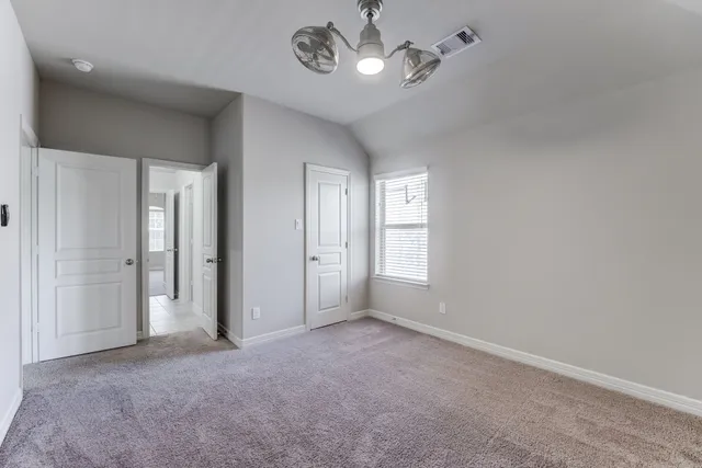 an empty room with chandelier fan and windows