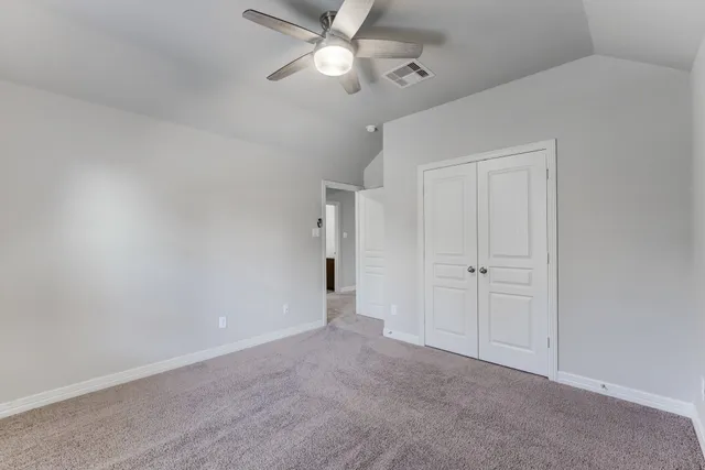 a view of an empty room and chandelier fan