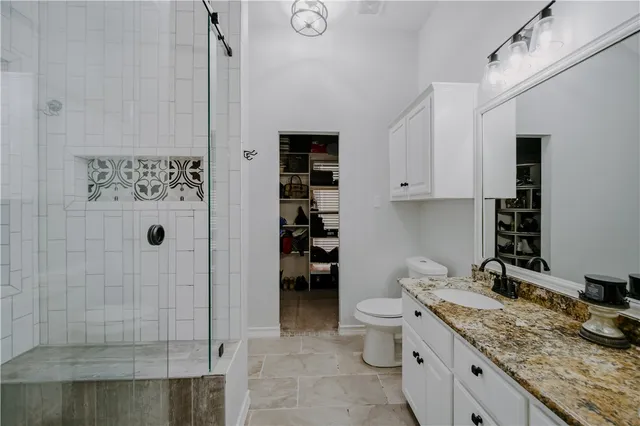 a bathroom with a granite countertop sink a toilet and shower