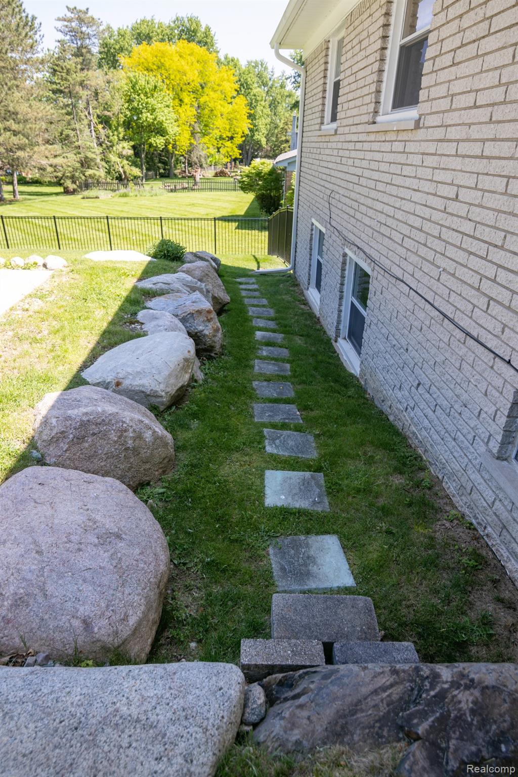 724 Sandstone Drive Rochester, MI 48309 - Photo 55 of 60 Exterior brick facade with multiple windows, featuring a stepping stone pathway set in grass